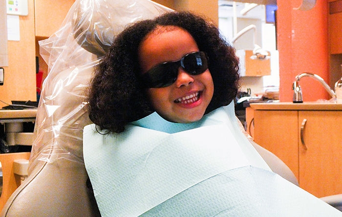 Child in dental chair with sun glasses